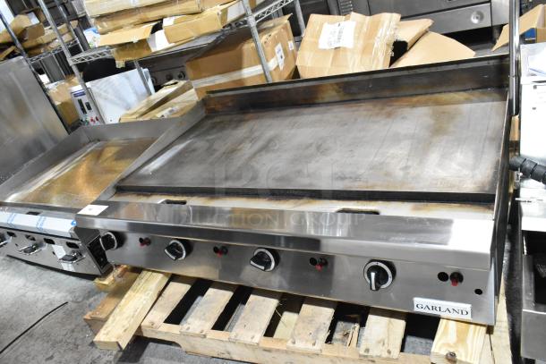 Garland stainless steel natural gas powered flat top griddle, like new condition, with control knobs and branding visible.