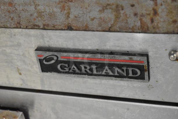 Garland stainless steel commercial electric griddle, countertop model, 240 volts, shows some wear. Garland logo visible.