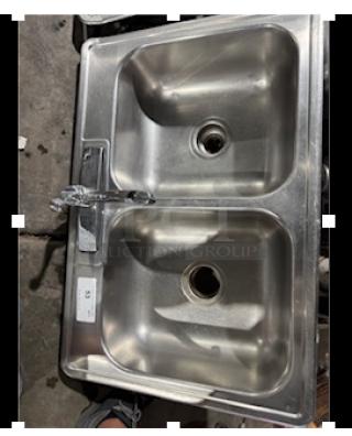 Stainless steel drop-in double sink with chrome faucet, used condition, visible label with model information.