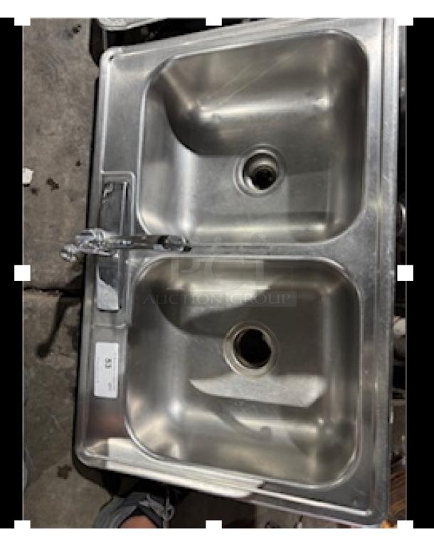 Stainless steel drop-in double sink with faucet, good condition, visible sticker with number, suitable for kitchen use.
