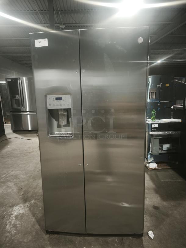 GE 21.8 cu ft counter-depth side-by-side refrigerator, model GZS22IYNFS. Fingerprint-resistant stainless steel, visible dent on lower door.