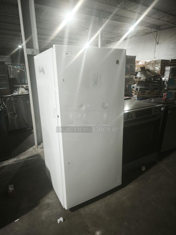 GE 14.1 Cu. Ft. Frost-Free Upright Freezer, model FUF14DLRWW, in used condition with visible dents. Garage-ready design.