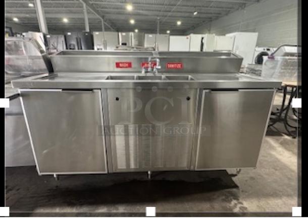 Commercial stainless steel three-compartment sink with two-door cooler, features labeled "Wash," "Rinse," "Sanitize," in excellent condition.