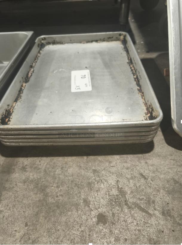 Commercial heavy-duty aluminum half-sheet pans, stack of 5, used condition with visible wear and sticker labeled "70 x5."