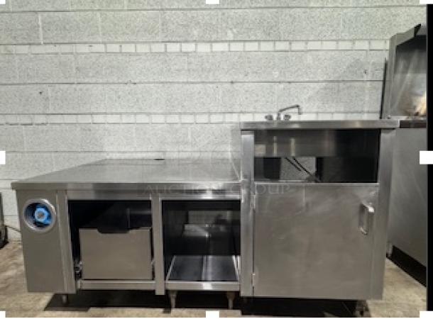 Custom stainless steel table with single sink, storage compartments, and faucet. Ideal for commercial use. Appears in good condition.