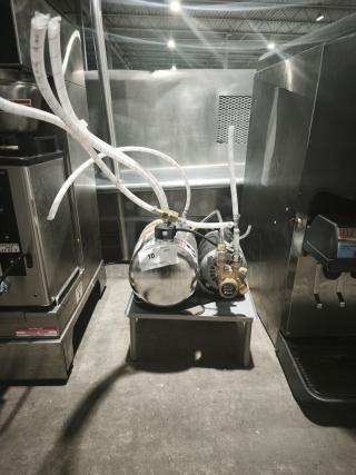 US Motors S55JXPTV-8269 Carbonator Pump Motor, stainless steel, with attached hoses and visible label, on display table.