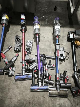 Dyson V11 Torque Drive PLUS cordless vacuum cleaners, various colors, with attachments. Visible labels show model and condition.