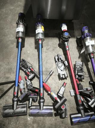 Dyson V11 Torque Drive PLUS cordless vacuums in multiple colors, with attachments. Tags display item numbers 99-102.