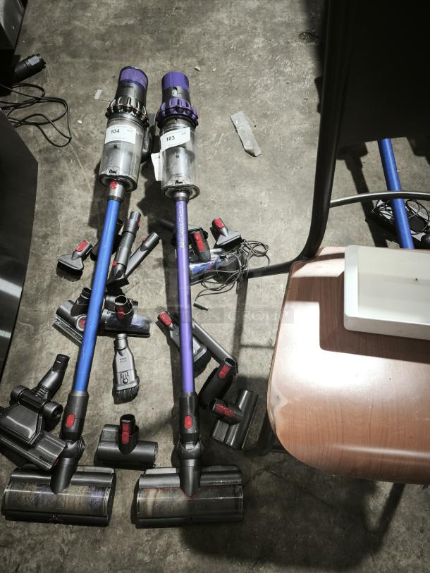 Dyson V11 Torque Drive PLUS cordless vacuum, includes multiple attachments, visible usage marks, tags "103" and "104."