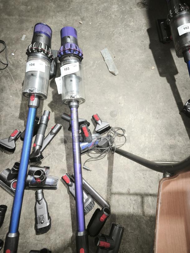 Dyson V11 Torque Drive PLUS vacuum cleaners with attachments, labeled 103 and 104. Items show some wear.