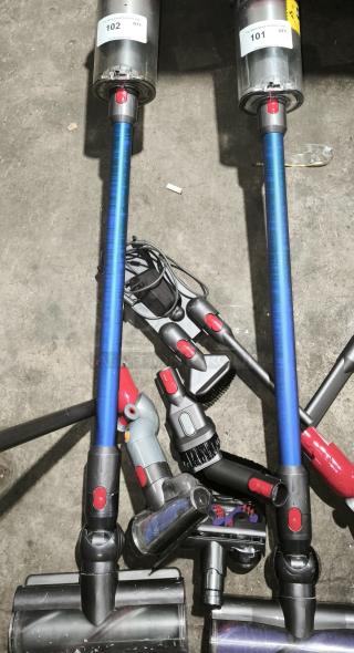 Dyson V11 Torque Drive PLUS cordless vacuum with blue stick, attachments, and visible auction labels 101, 102. Excellent condition.