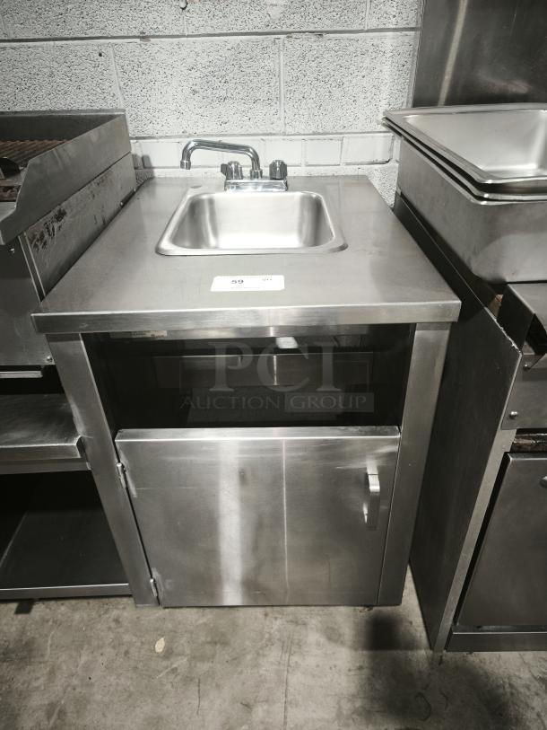 Stainless steel custom table with single sink and faucet, storage cabinet below. Good condition. Auction tag: #59.