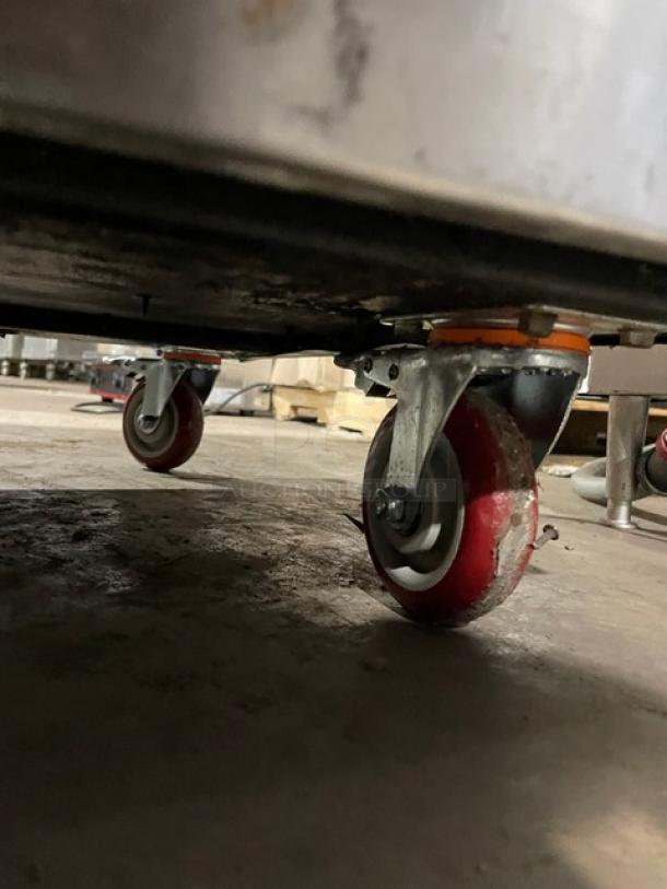 American Range commercial 10 burner stainless steel range with double oven, backsplash, overhead salamander shelf, on red casters.