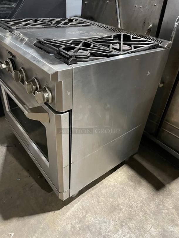 Monogram stainless steel gas-powered 4-burner range/oven combo with wired oven rack, on legs, in good condition.