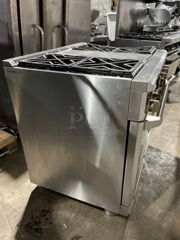 Monogram stainless steel gas range/oven combo with 4 burners, wired oven rack, on legs. Features sturdy controls, clean condition.