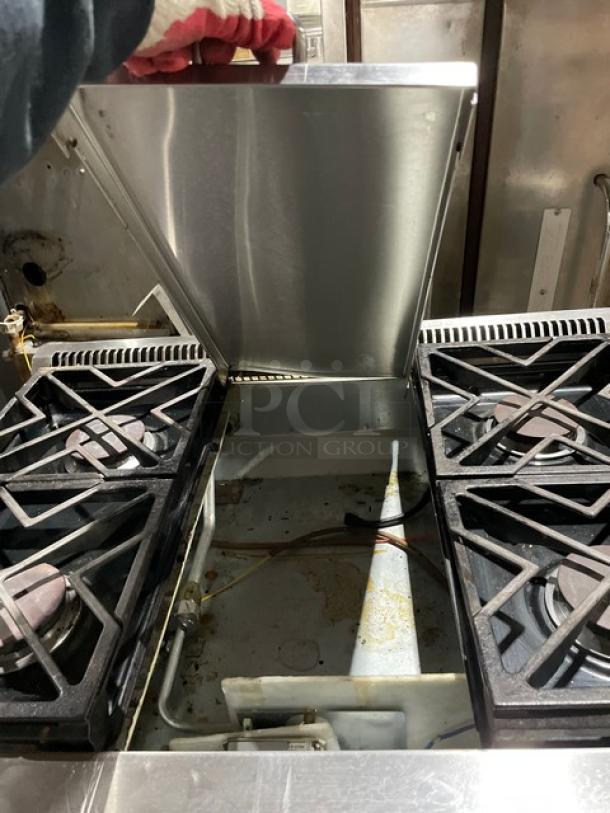 Monogram stainless steel 4-burner gas range/oven combo with wired oven rack on legs. Commercial use, good condition.