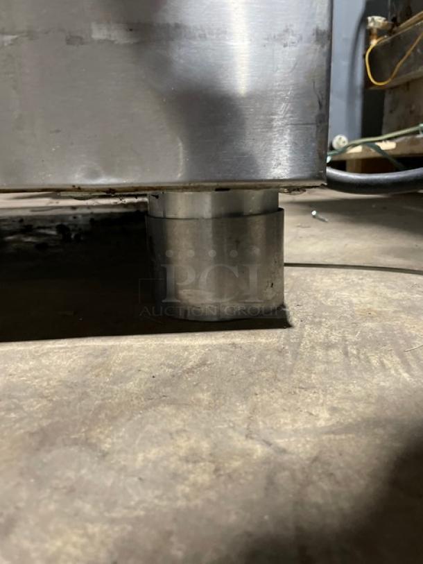 Monogram stainless steel gas range/oven leg. Durable construction, part of commercial 4-burner unit with wired oven rack.