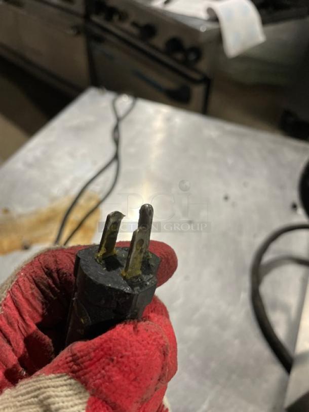 The image shows a close-up of a three-prong electrical plug attached to a Waring Panini Supremo Series Grill, Model WPG250T.