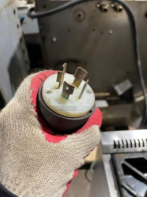 Gloved hand holding a power plug for the Structural Concepts Encore Series Commercial Refrigerated Display Case.