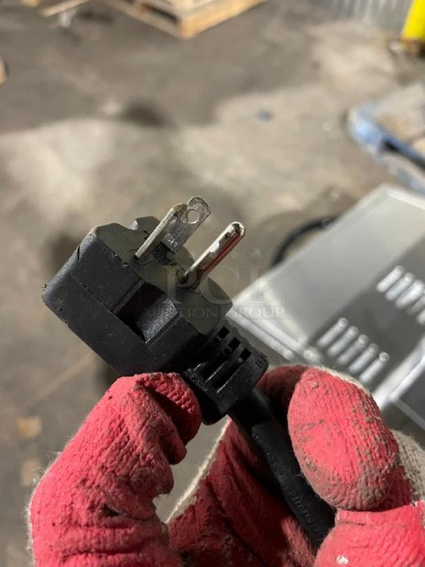 Close-up of a power plug for Cookline ES4000L salamander broiler, showing three-prong plug with gloved hand.