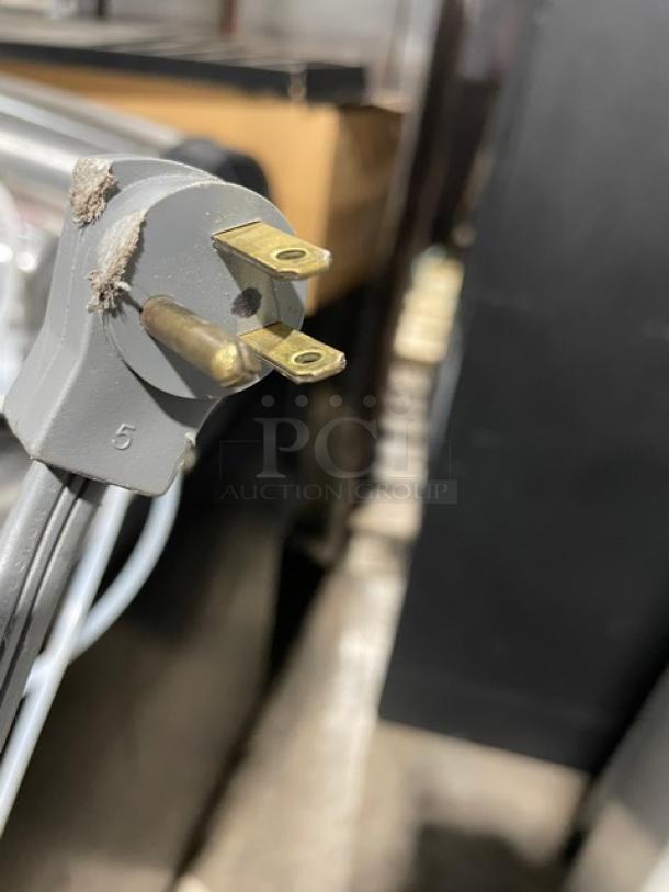 Close-up of Sub-Zero 601RS refrigerator power plug showing three-prong design and slight wear.