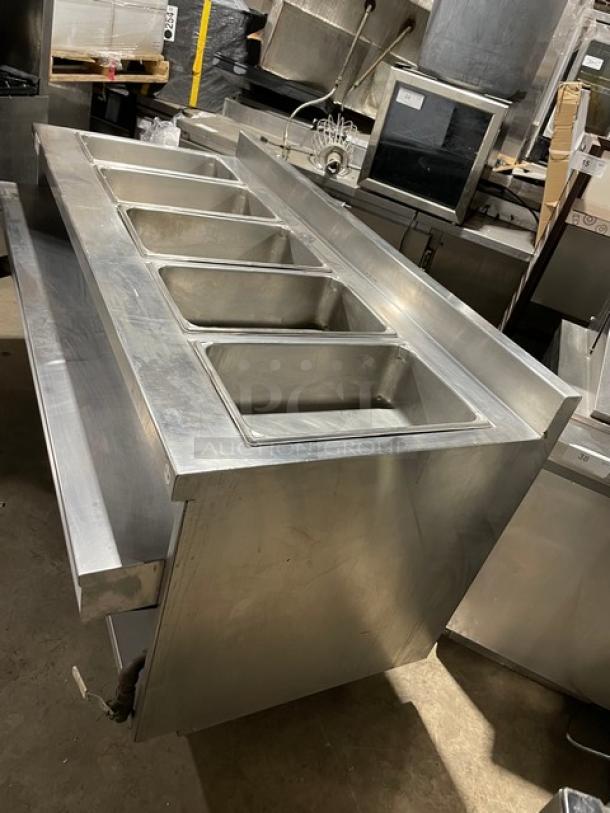 Delfield stainless steel 5-well gas heated steam table with lower tray slide, single undershelf, and up-turned backsplash.