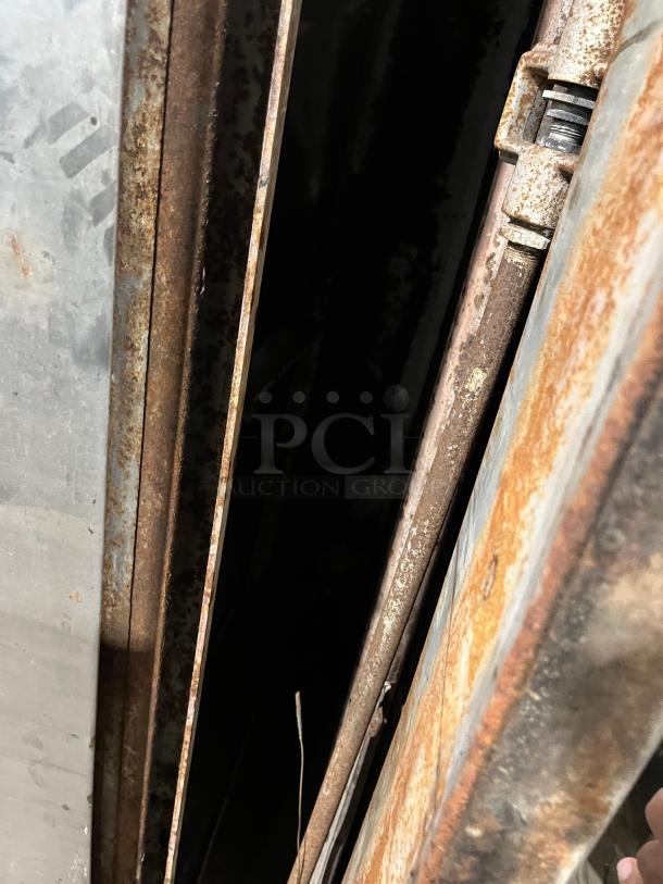 Bakers Pride double-stacked pizza deck oven with visible rust, hinges, and natural gas fittings. Commercial stainless steel.