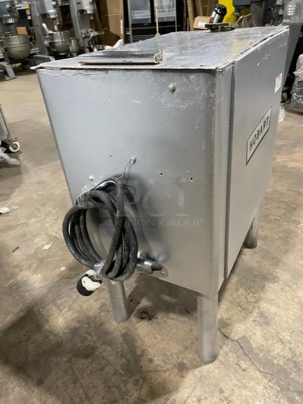Hobart commercial electric meat grinder on legs, heavy-duty, silver, used condition, with visible power cord.
