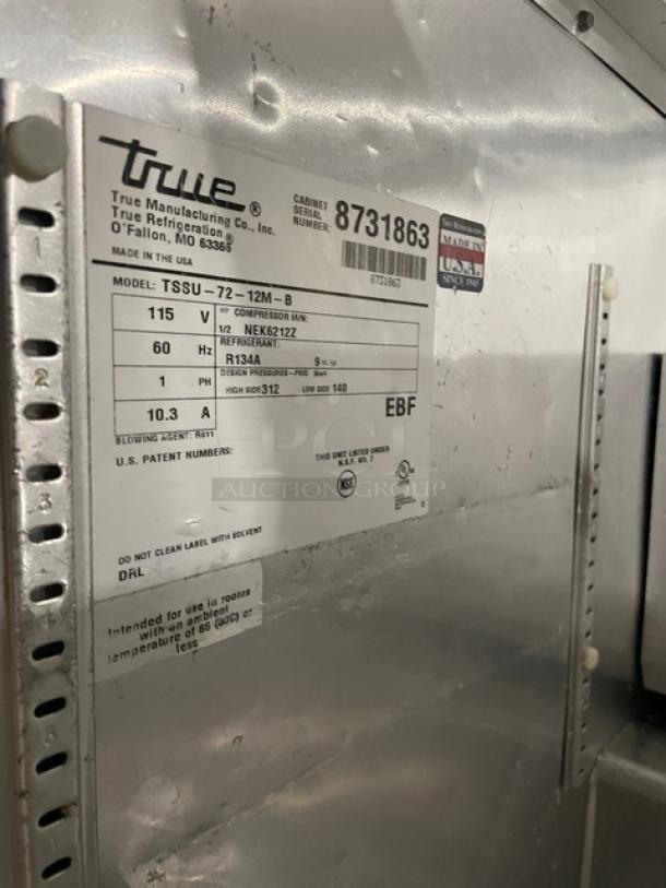 True TSSU-72-12M-B model label on stainless steel prep table, 115V, serial number 8731863, features include overhead shelf.