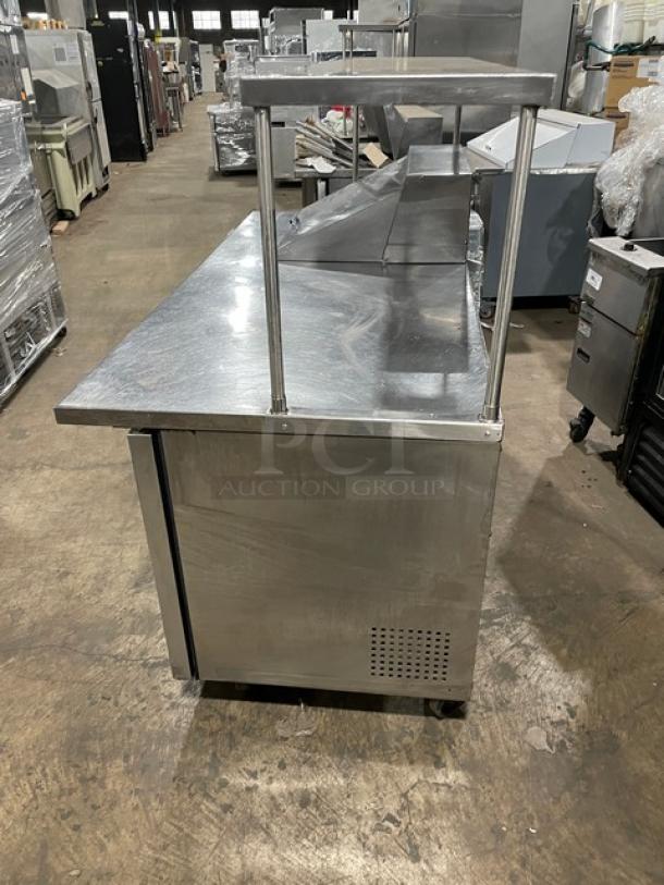 True Commercial Stainless Steel 3 Door Refrigerated Prep Table, model TSSU-72-12M-B, with overhead shelf, wired rack, casters.
