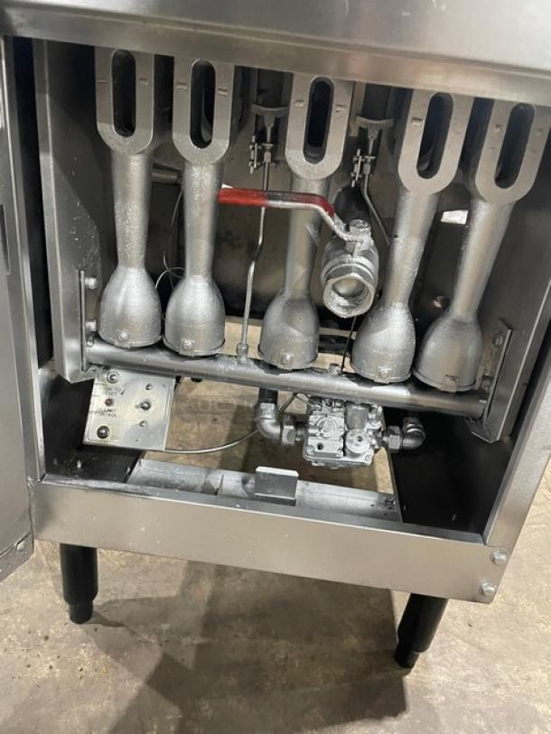 Commercial stainless steel natural gas fryer with back splash, basket hanger, and fry basket. In good condition, on legs.