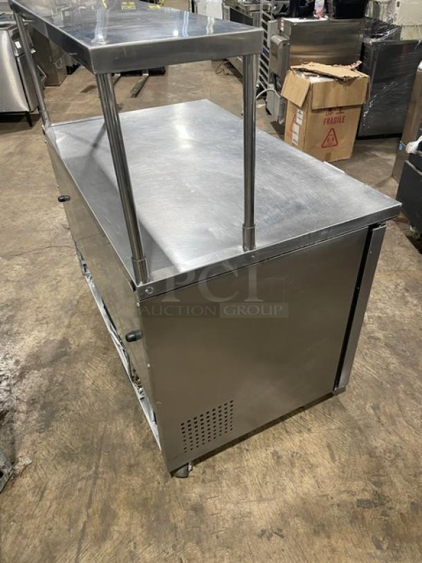 True commercial stainless steel 2-door worktop refrigerator with overhead shelf and poly-coated wire rack, Model TUC-48, on casters.