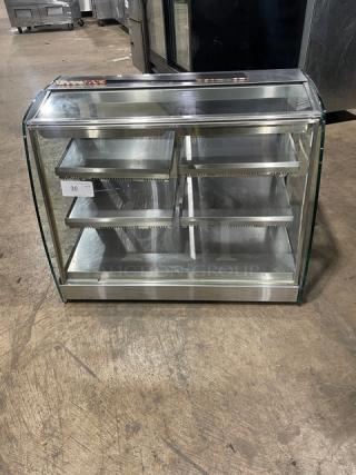 Commercial stainless steel electric heated food display case with multi-level shelves and rear double glass sliding doors.