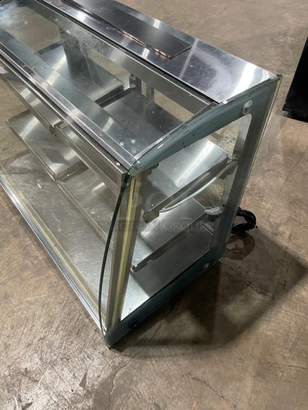 Commercial stainless steel electric heated food display case with multi-level shelves and rear double glass sliding doors.