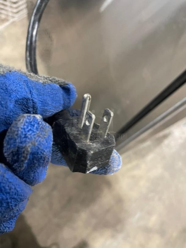 Close-up of a power plug for the Turbo Air MST-28-12 refrigerated prep table, shown in gloved hand.