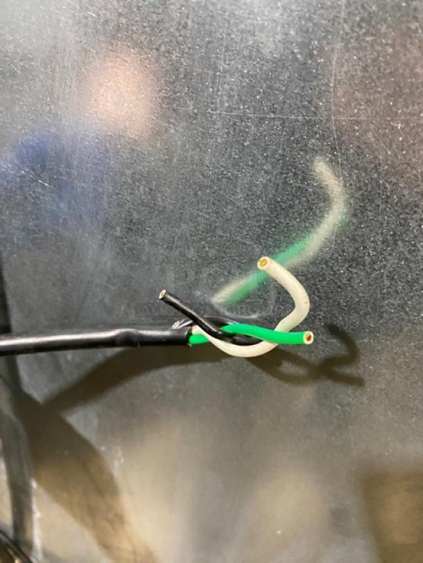 The image shows three loose electrical wires in black, white, and green against a metallic surface.