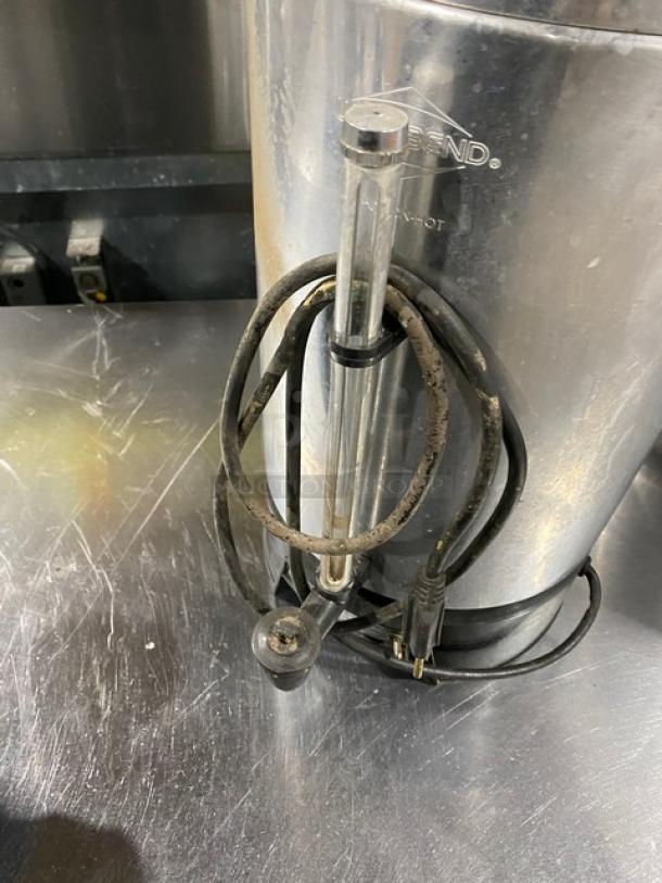 Commercial stainless steel electric-powered insulated coffee urn, showing wear. Features visible power cord and level indicator.