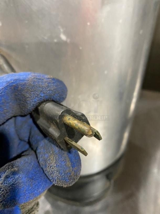 Commercial stainless steel insulated coffee urn with visible worn power plug. Electric powered, suitable for large-scale use.