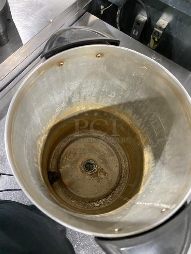 Stainless steel electric coffee urn, interior view, used condition, visible wear, insulated for commercial use.