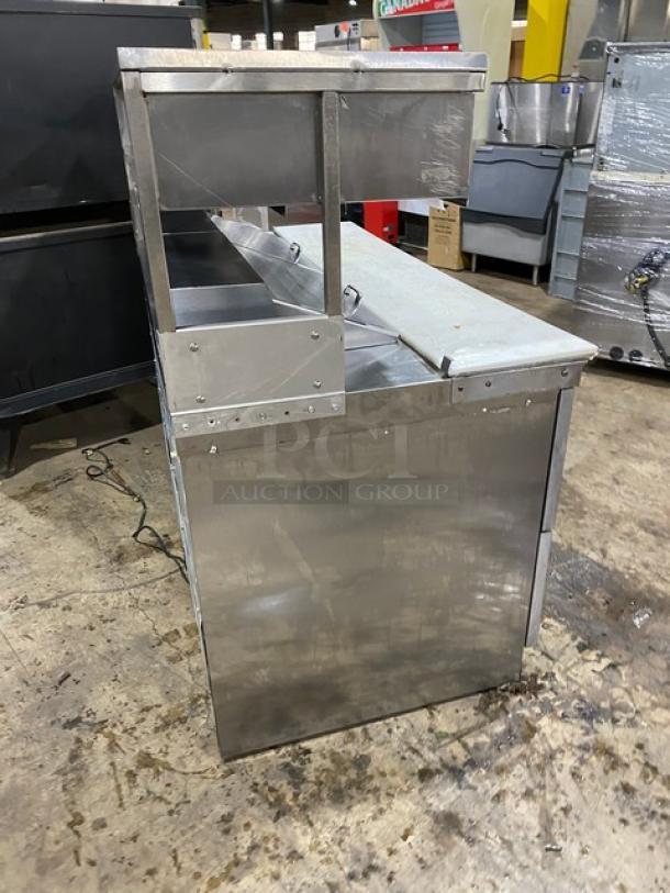 Commercial stainless steel refrigerated prep table, four drawers, bain marie style, overhead shelf, cutting board included.