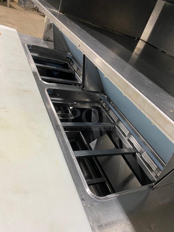 Commercial stainless steel 4-drawer refrigerated salad/sandwich prep table with overhead shelf and cutting board.