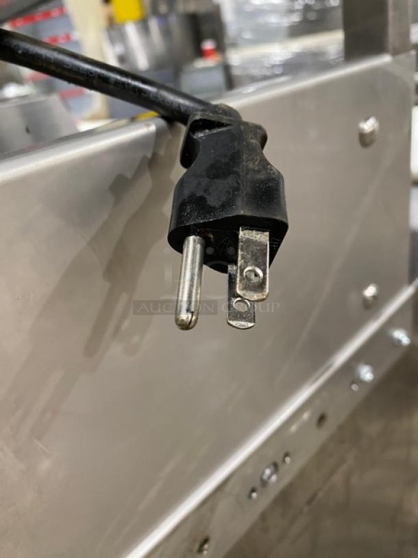 Black plug of a commercial stainless steel refrigerated prep table.