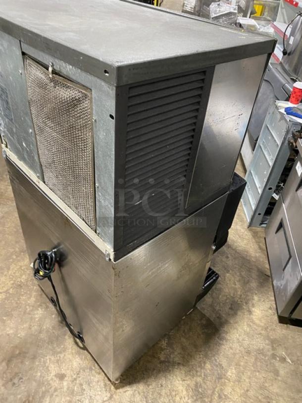 Manitowoc Q Series stainless steel ice machine, model QD0452A, with beverage dispenser and drip tray on legs.