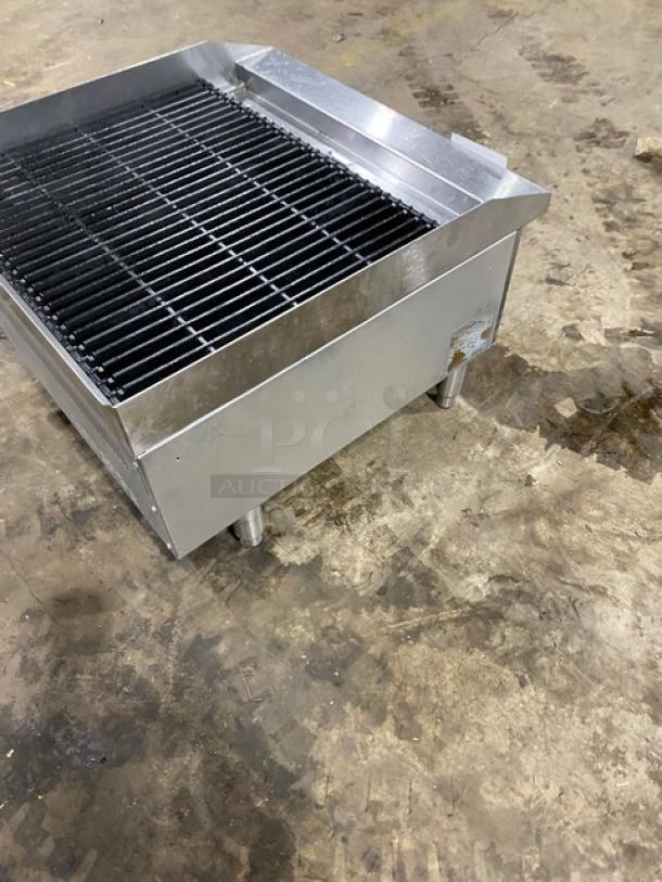 Commercial stainless steel gas-powered countertop char broiler with wavy grates and legs, visible wear.