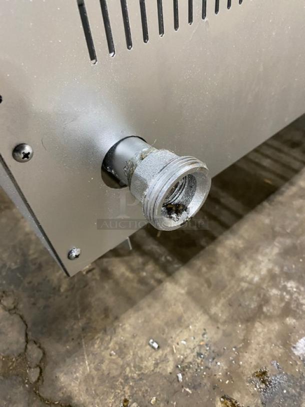 Commercial stainless steel gas-powered countertop char broiler with wavy grates, on legs. Secure connection shown.