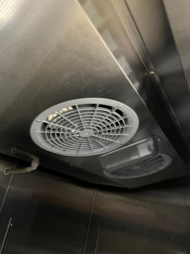 Migali C-2F freezer interior view, showing stainless steel construction and cooling fan. Poly coated wired rack included.