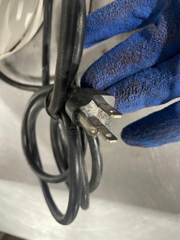 Close-up of a power cord plug held in a gloved hand. Part of the Synesso/Mahlkonig espresso machine and grinder.
