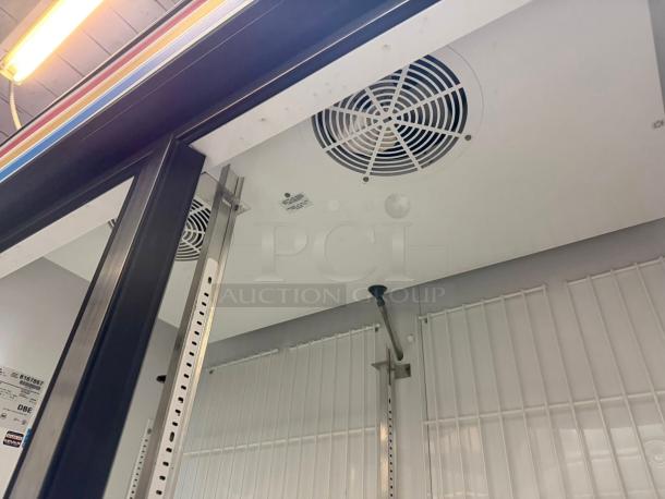 True GDM-49F-LD double door glass freezer interior, showing circulation fans, metal shelving brackets, and interior lighting.
