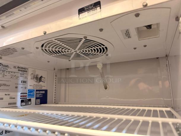 True GDM-10-58-HC-LD Coca-Cola display fridge interior, white shelves, fan vent, labels indicating model and features.