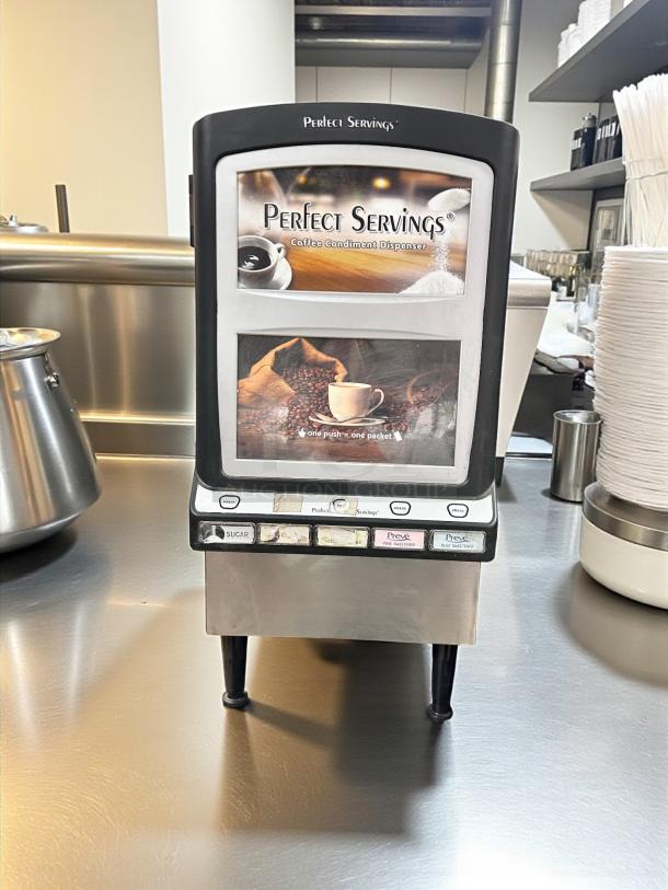 "Perfect Servings" coffee condiment dispenser on a stainless counter with labeled buttons for sugar and sweeteners.